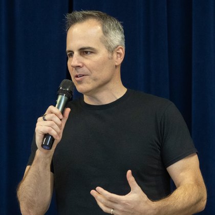 Chad Kempel, anti-bullying assembly speaker, speaking on stage with a microphone