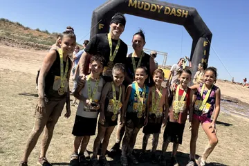 Chad Kempel with his wife and kids, all wearing medals, at the Muddy Dash finish arch