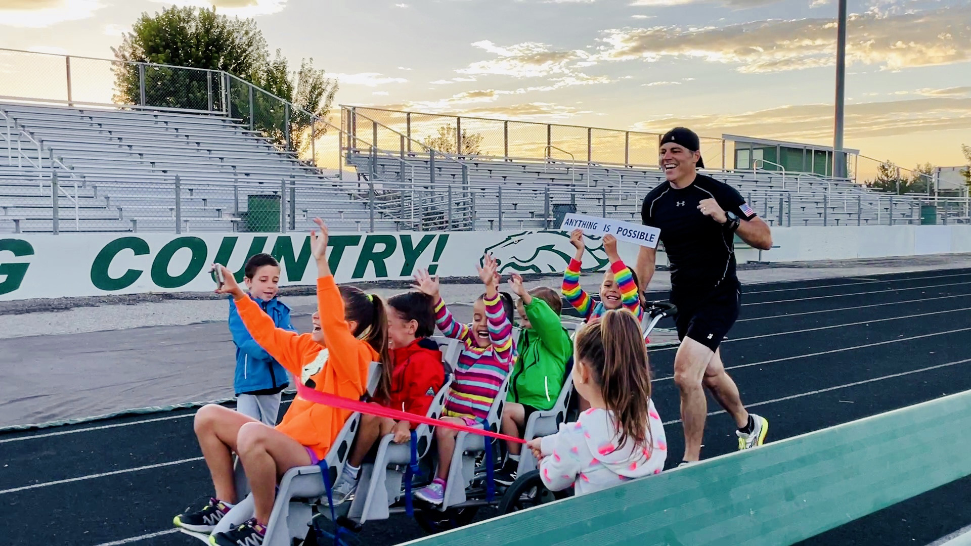 Chad Kempel finishing the 1 kilometer record attempt as his children hold the ribbon