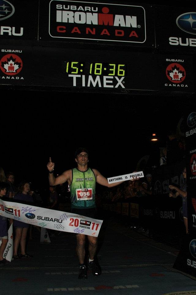 Chad Kempel finishing Ironman Canada in 2011 holding the Anything Is Possible sign
