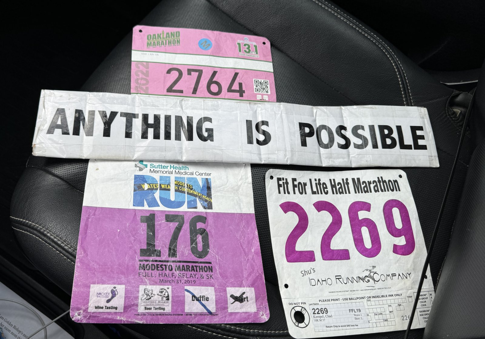 The Anything Is Possible sign with three race bibs