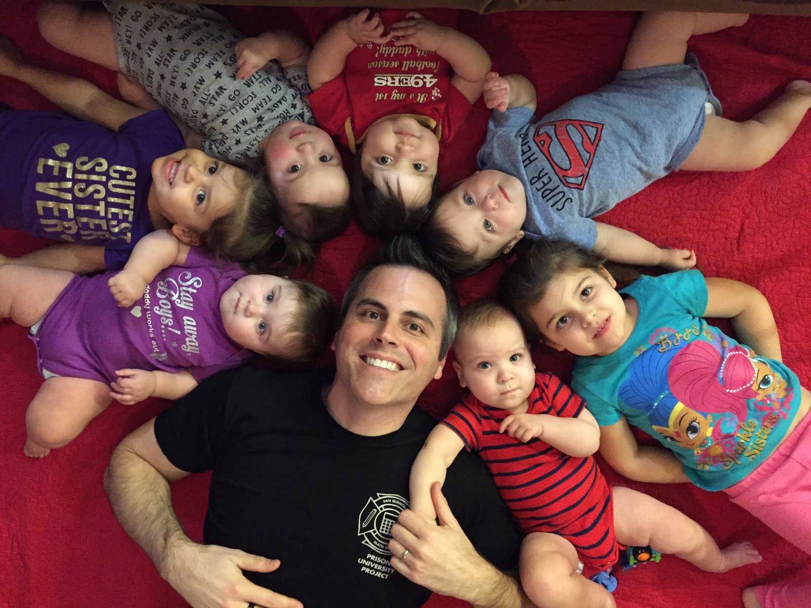 Chad Kempel lying on a blanket surrounded by his seven children